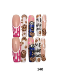 Press-on nails displayed featuring various designs including pink and white drip patterns, brown cookie details, and blue monster graphics. 
