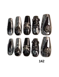 Coffin-shaped press-on nails. The nails are glossy black and silver with various gothic and fantasy designs including skulls, a lion, a snake, and a skull with a crescent moon.