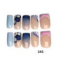 Press-on nails include solid pastel blue, beige with dark blue floral motifs, beige with blue ombre gradients, beige with blue swirls, and beige with pink and blue marbling.
