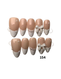Press-on nails featuring a classic beige and white French tip design with some decorated nails adorned with small pearls and a bow. 