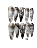 A set of 10 stiletto-shaped press-on nails. The nails feature a glossy black, white, and gray marbled pattern with silver metallic bead accents and two silver 3D floral designs.